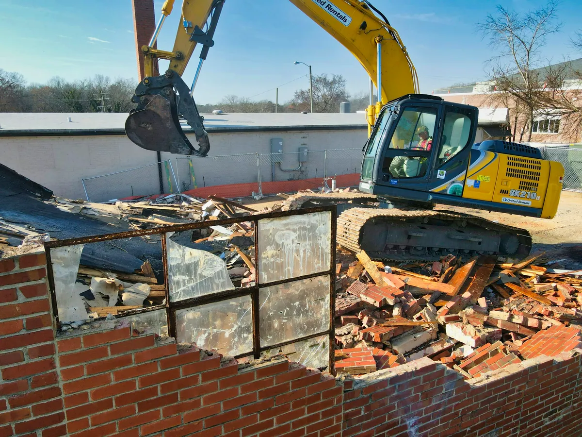 An excavator demolishing a brick building