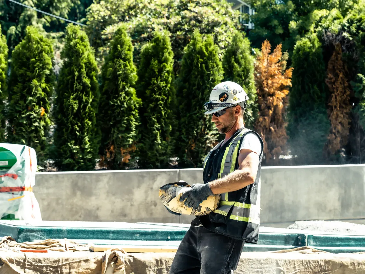 A crew member pouring concrete mix on a residential job site