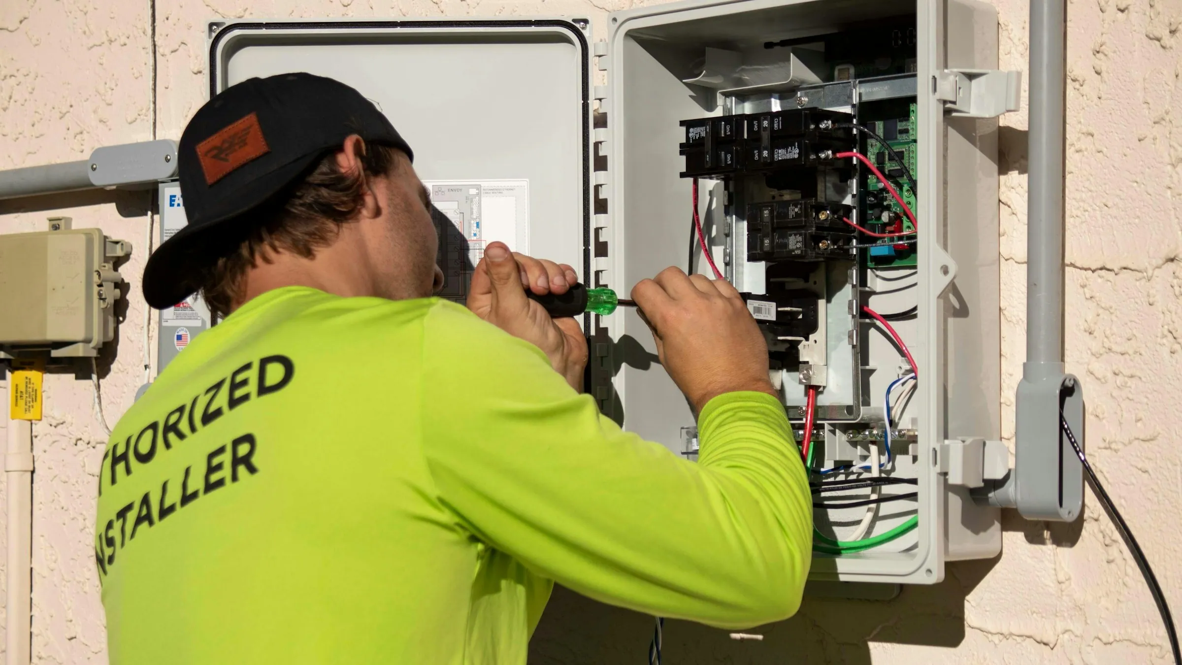 An electrician in a hi-vis shirt working on an electrical panel