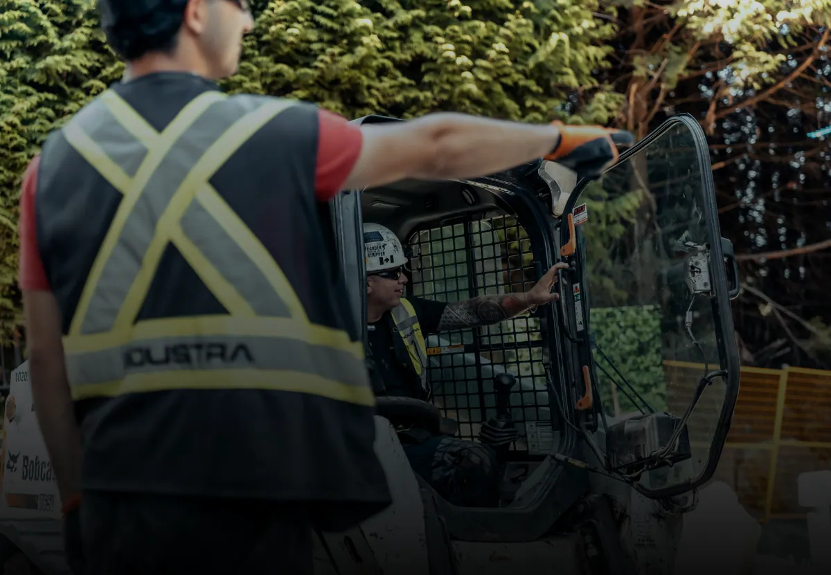 A site lead directing a skid steer operator on a residential job