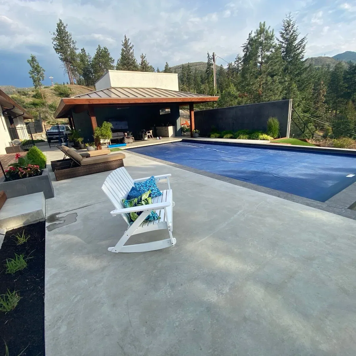 A KCC concrete pool with a deck and pool house on a hillside
