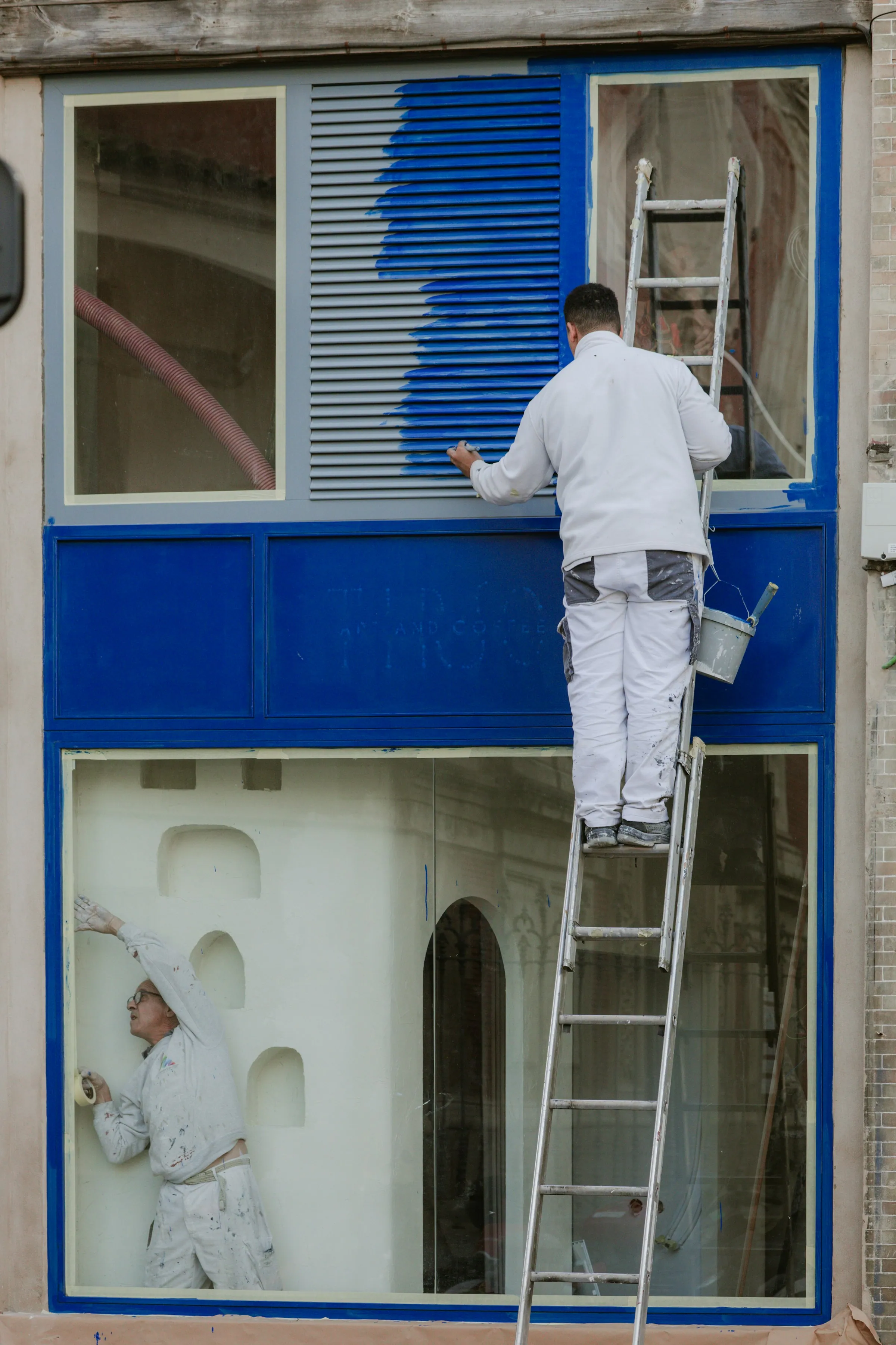 A painter on a ladder painting the outside of a building