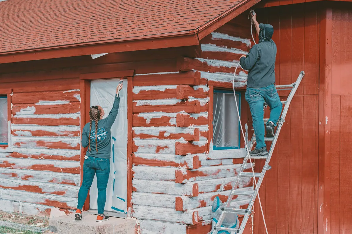 A painter on a ladder painting the outside of a house