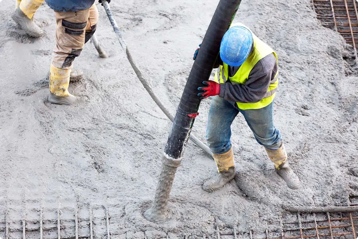 Worker pouring concrete from a pump hose