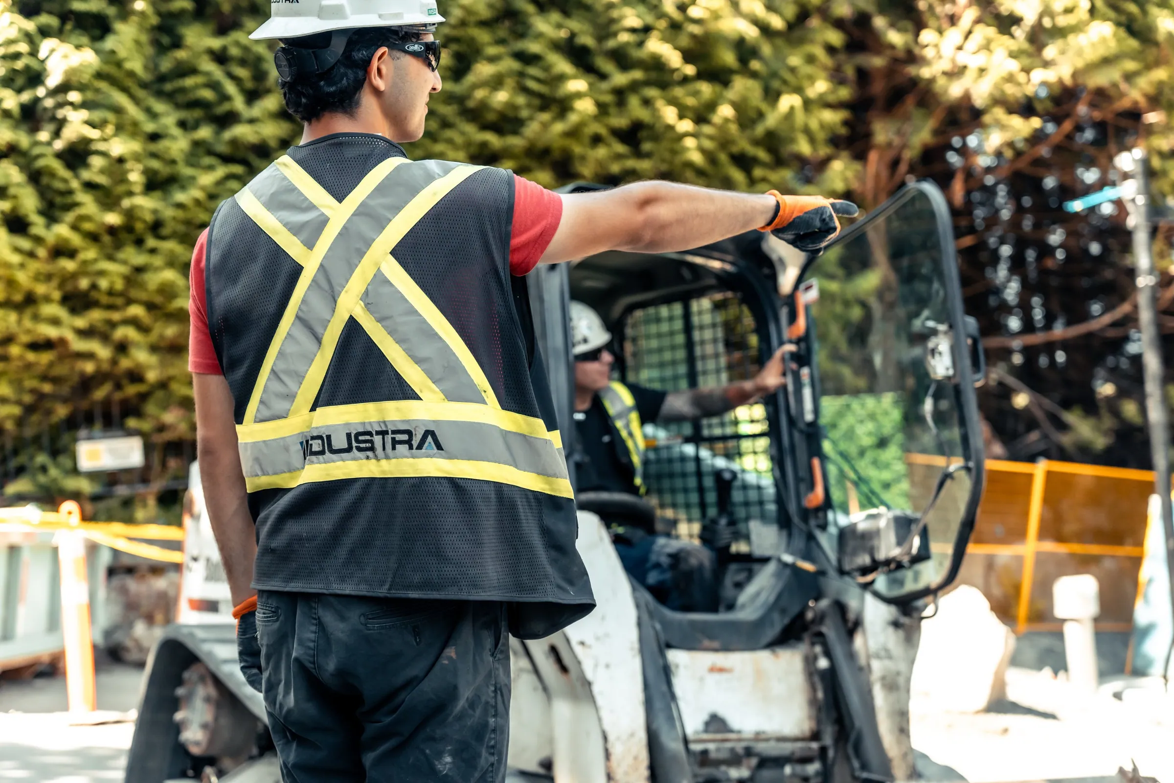 Site supervisor directing a skid steer operator