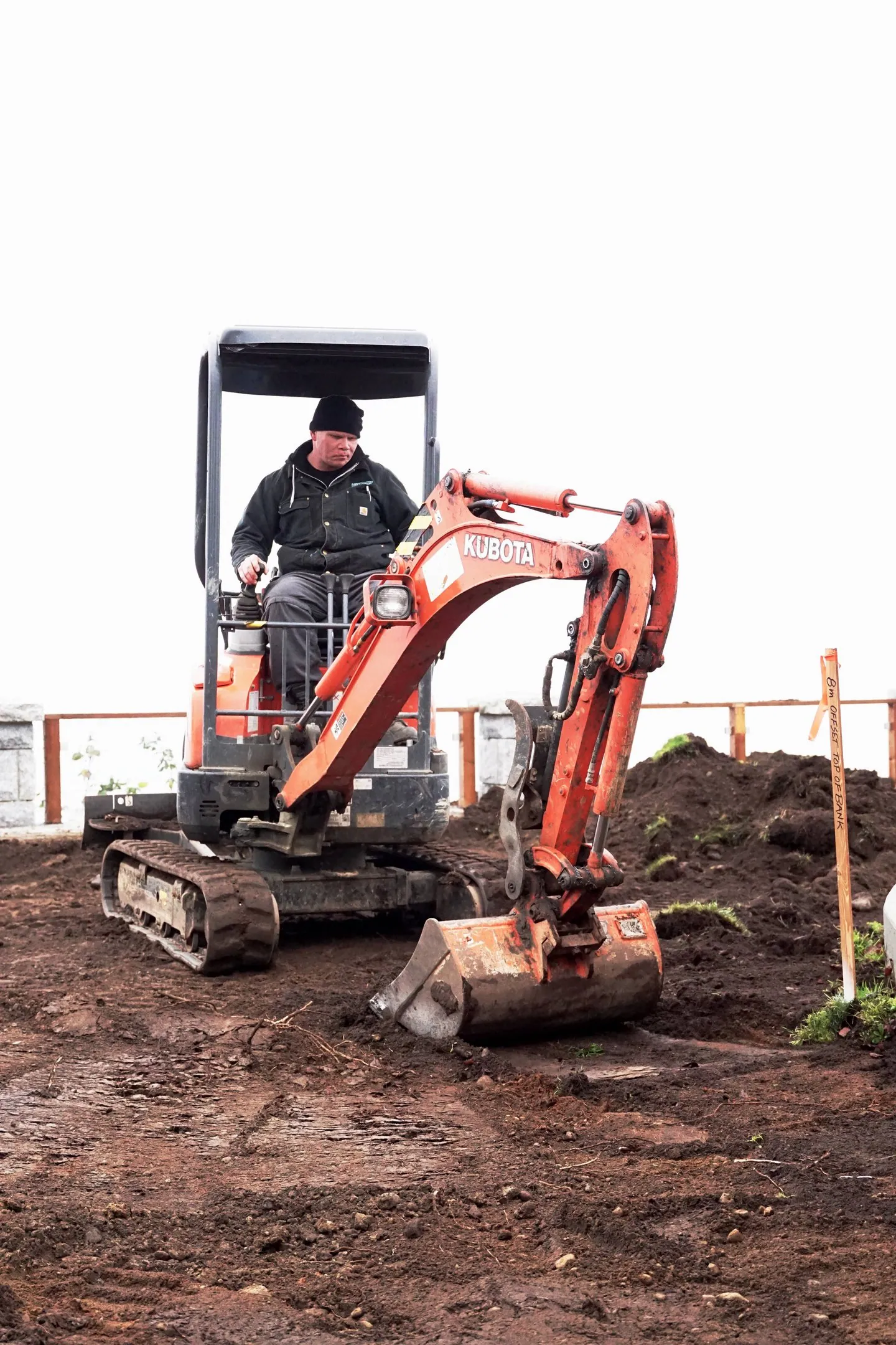 An operator in a mini excavator on a residential lot