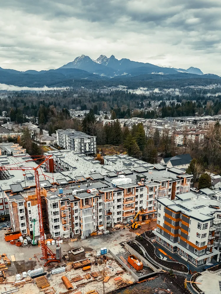 Aerial view of a multi-building construction site with mountains behind