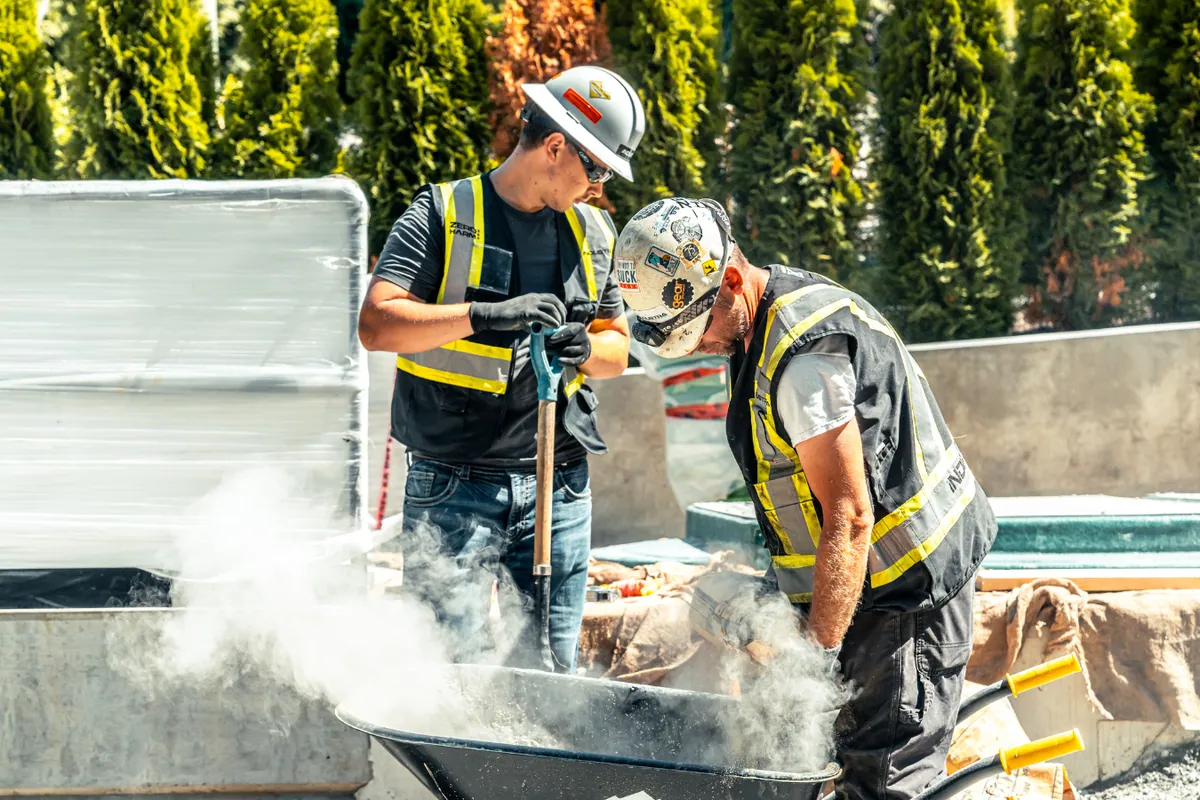 Two crew members mixing concrete on a job site
